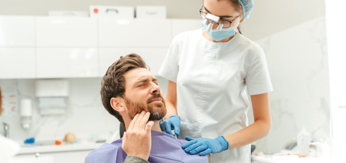 man holding his jaw in pain, damaged dental crown