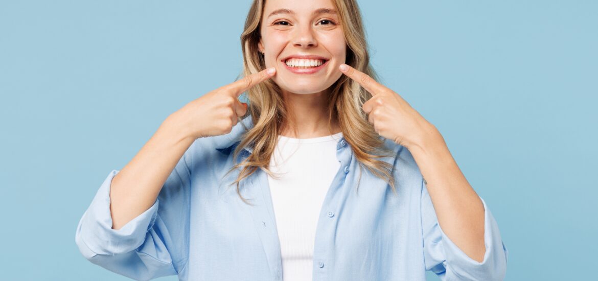 young woman showing off her flawless smile against a light blue background