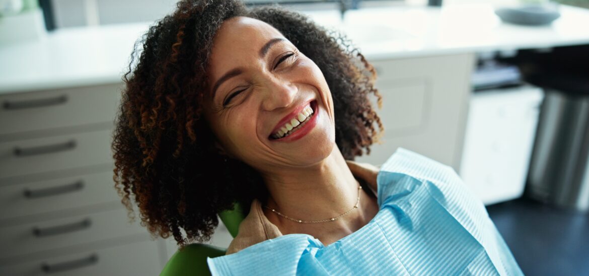 female patient smiling in dental office, talking to hygienist for dental hygiene