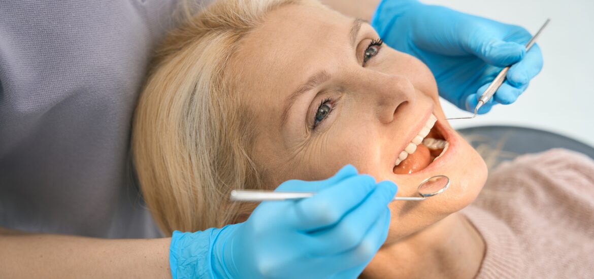 pretty woman having her bridge inspected by a dentist in blue gloves