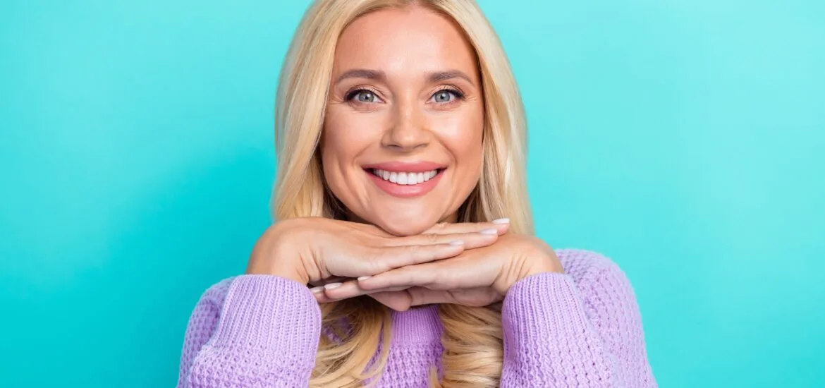 portrait of a woman smiling against a light blue background, new veneers
